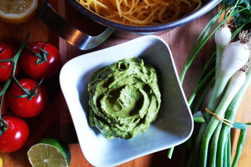 Pasta with creamy avocado sauce, herbs and vegan parmesan cheese